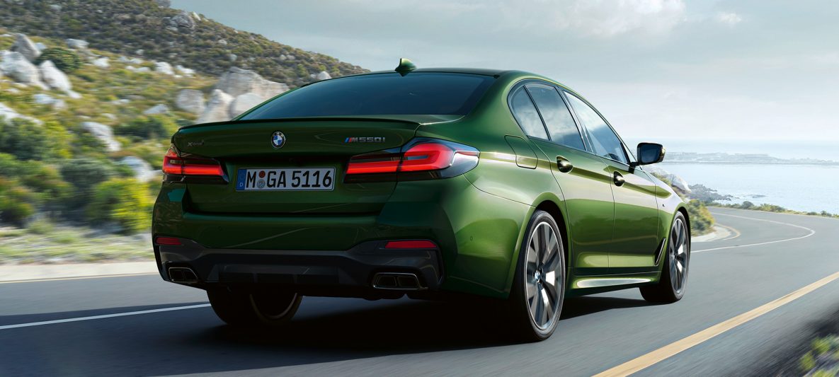 BMW M550i xDrive Limousine G30 LCI Facelift 2020 BMW Individual Verde Ermes metallic Heckansicht fahrend auf Landstraße