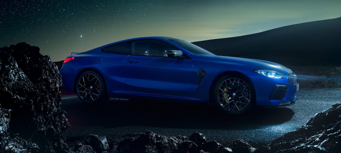 BMW M8 Competition Coupé in Marina Bay Blau metallic, stehende Dreiviertel-Seitenansicht bei Nacht.