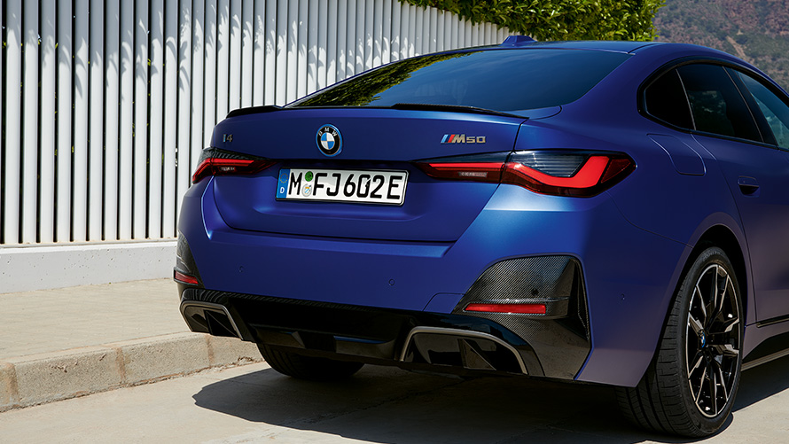 BMW i4 M50 G26 2021 BMW Individual Frozen Portimao Blau metallic Dreiviertel-Heckansicht stehend am weißen Zaun